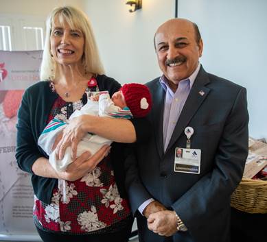 Director of Couplet Care Roberta Jones holds day-old Delilah Acevedo alongside hospital CEO Ed Mirzabegian during the Little Hats, Big Hearts ceremony